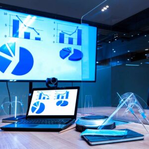 A professional data presentation design by AUZ Studio, featuring blue bar charts, line graphs, and pie charts displayed on a laptop and a large wall monitor in a modern corporate conference room.