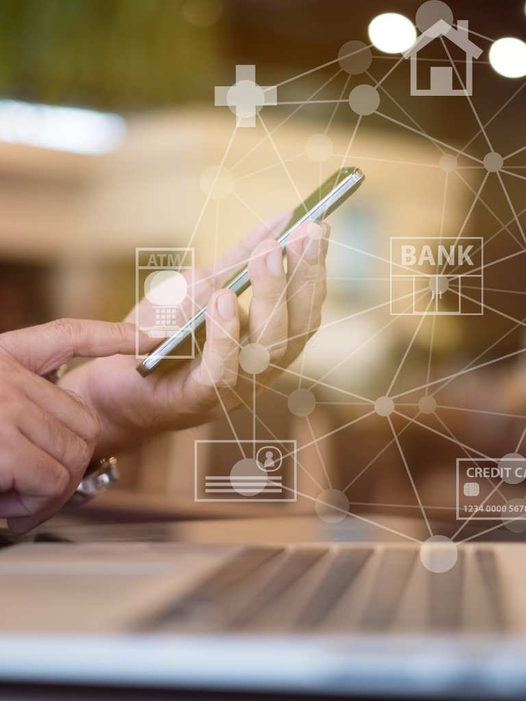 A close-up of a person's hands using a smartphone over a laptop, with a digital overlay of interconnected icons for banking, credit cards, ATM services, and home delivery for AUZ Studio.